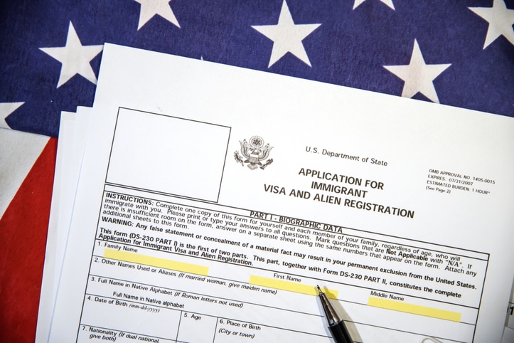 Person completing U.S. citizenship application forms beside an American flag