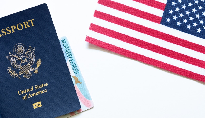 U.S. passport and permanent resident card displayed beside an American flag