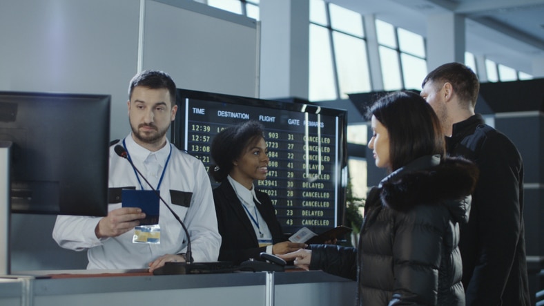 Airport personnel checking passports and travel documents at an immigration control point