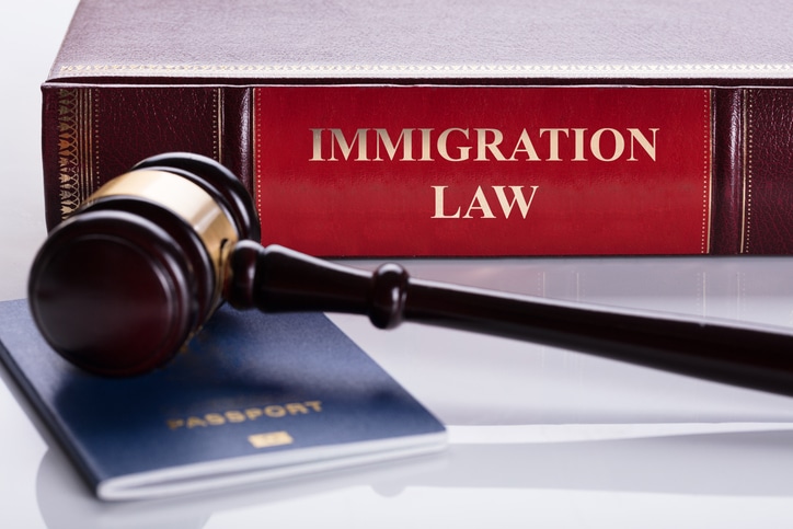 Passport and legal gavel beside immigration law book representing ICE detention and removal proceedings