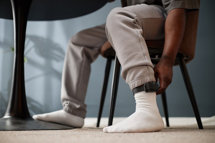 Person wearing an electronic ankle monitoring device as a condition of supervised release